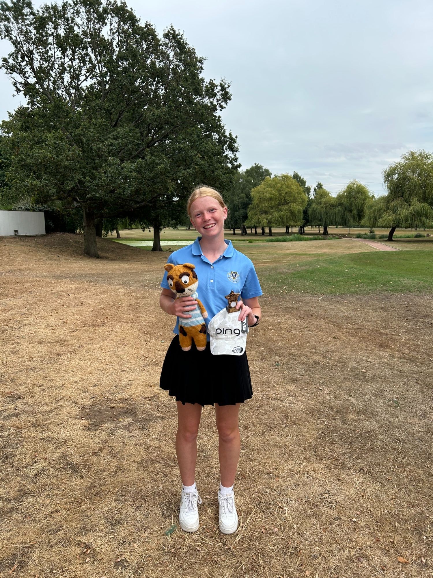 Image of student on golf course with trophy